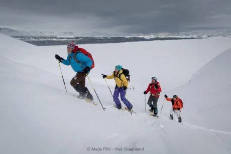 Snowshoers climbing up a hill near Sermilik ice fjord in East Greenland