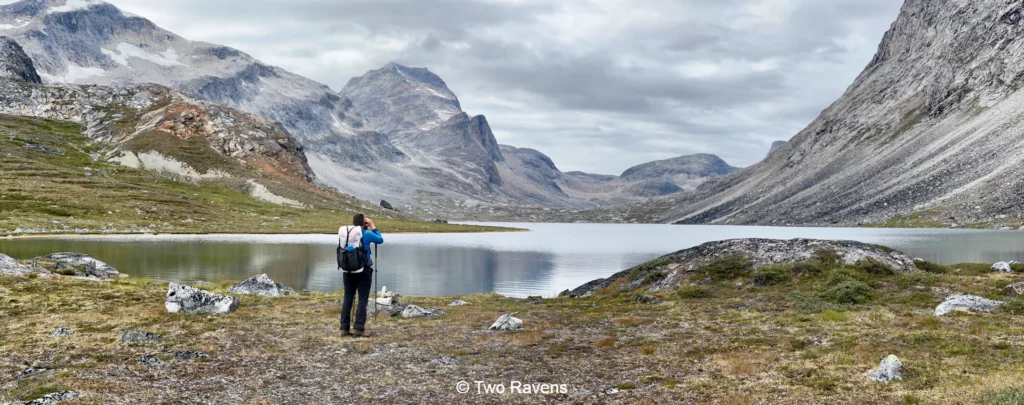 Trekking through Nuuk’s breathtaking fjords West Greenland. A hiker photographs a serene mountain lake.